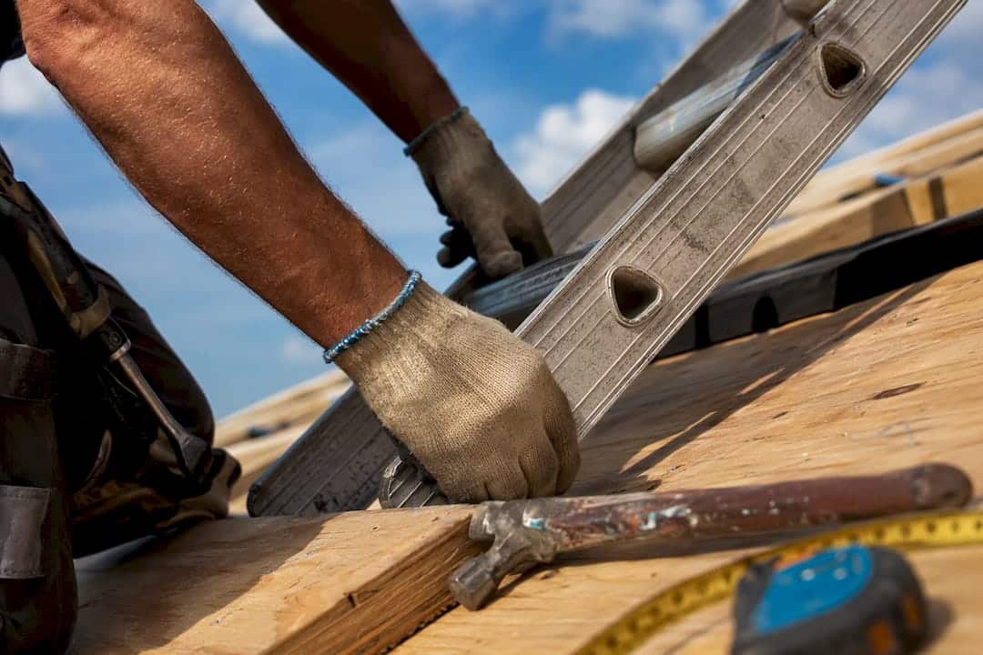 Contractor hands gripping roof ladder and tools